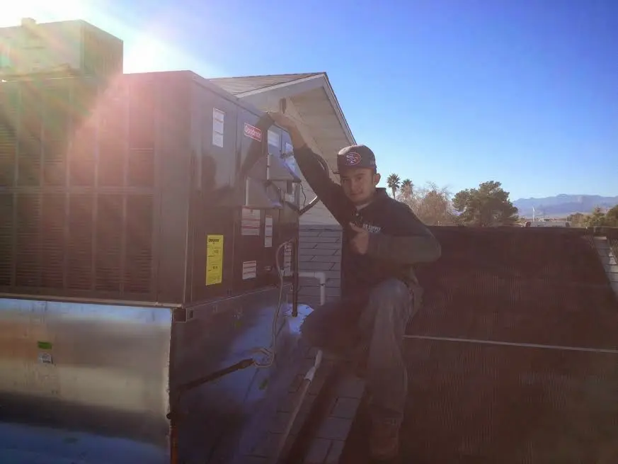 HVAC technician performing AC Tune-Up on a rooftop unit in Tarrant